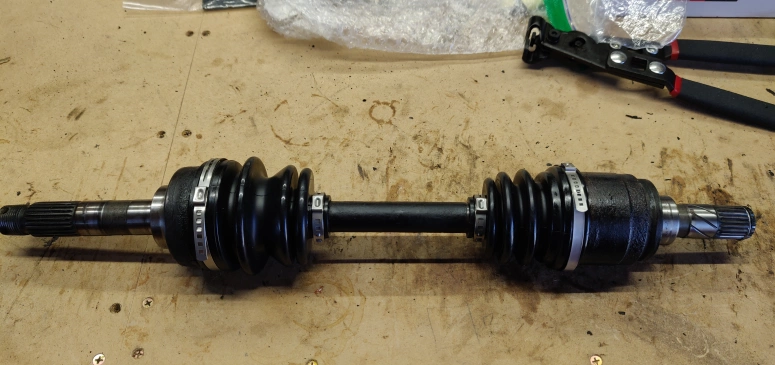 CV axle with new CV boots on a bench