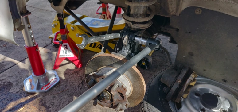 Using a breaker bar to loosen the strut bolts on the suspension