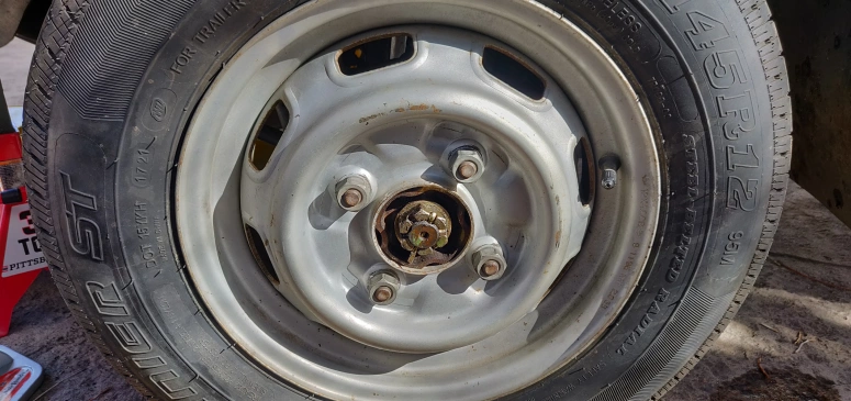 Plastic cap removed from wheel exposing axle nu